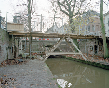 838529 Gezicht op de Paulusbrug over de Nieuwegracht te Utrecht, die gerestaureerd wordt.